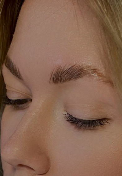 Close-up of a woman's face showing freshly groomed eyebrows and eyelash extensions